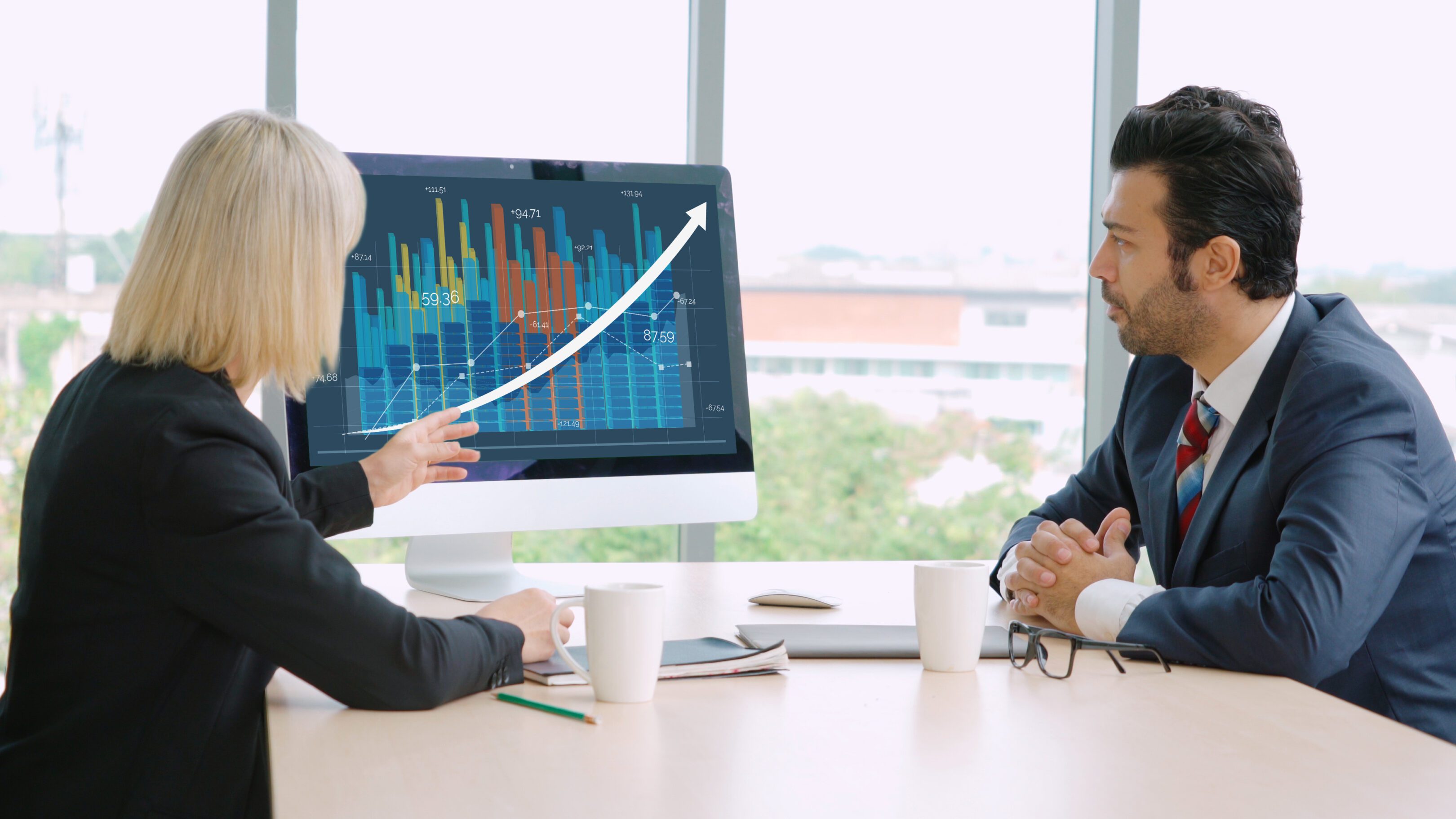 Two professionals discussing data on computer.